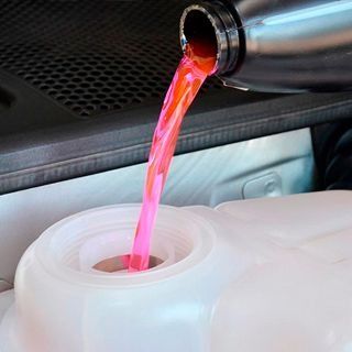 Se vierte una botella de líquido rosa en un recipiente de plástico.