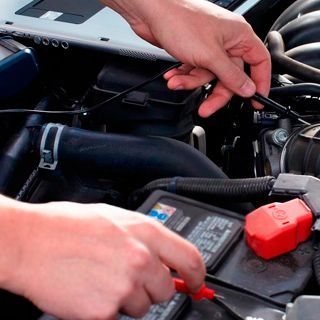 Un primer plano de una persona trabajando en una batería de automóvil.