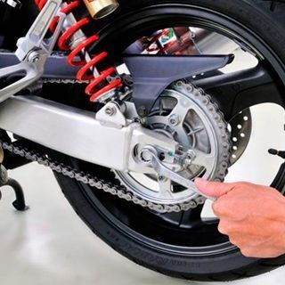 Una persona está trabajando en una motocicleta con una llave inglesa.