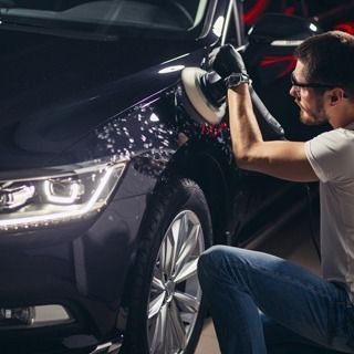 Un hombre está puliendo un coche con una pulidora.
