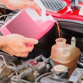 Una persona está vertiendo aceite en el motor de un automóvil.