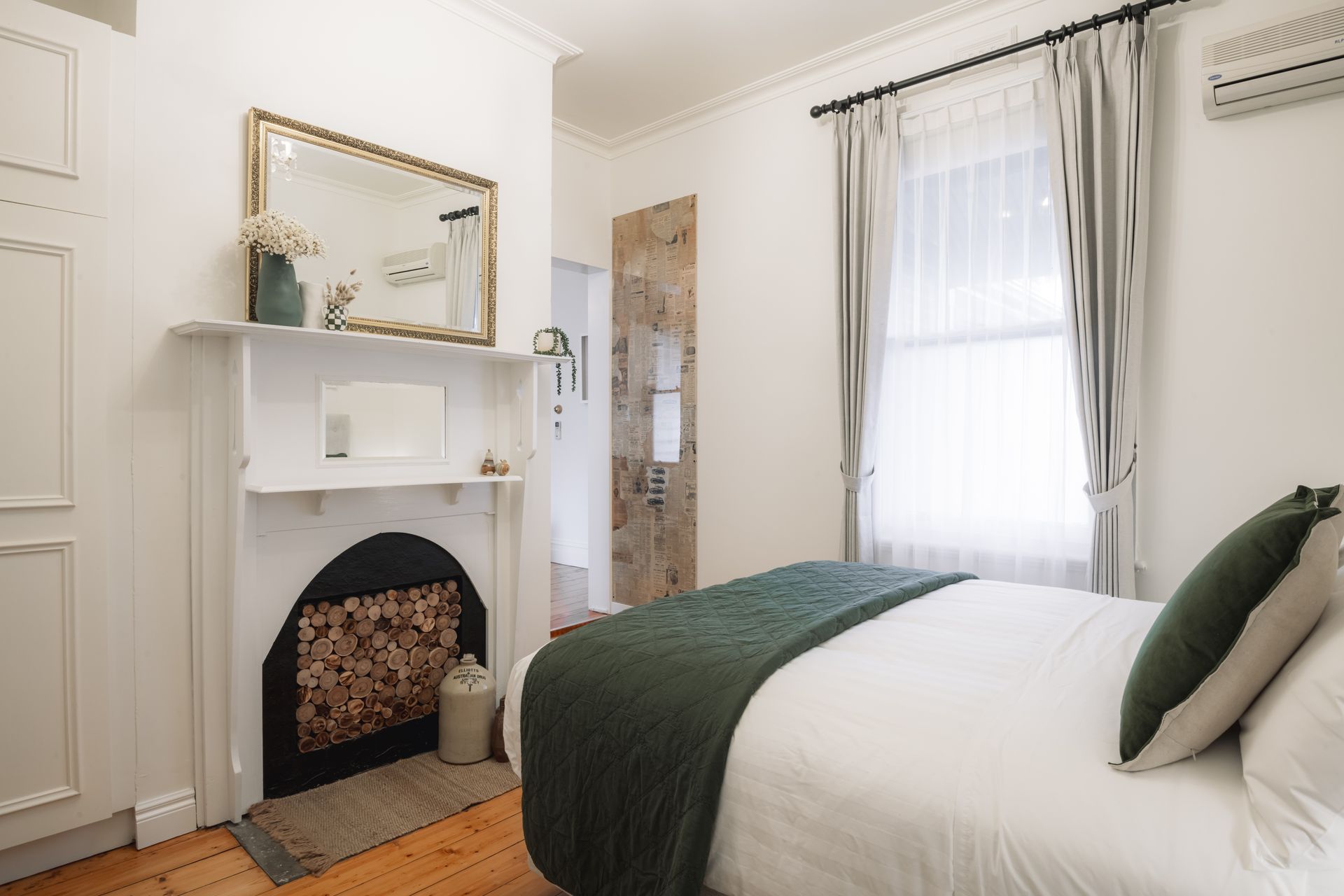 A bedroom with a bed , fireplace , mirror and window.