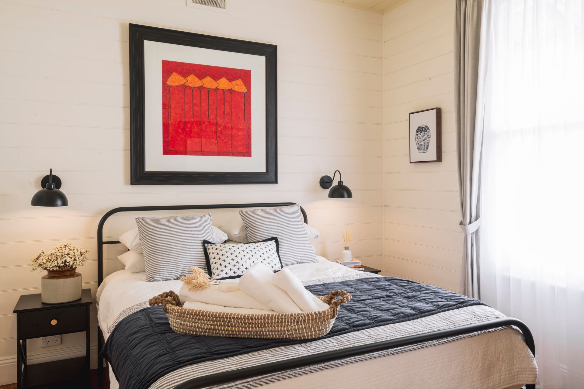 A bedroom with a bed and a picture on the wall above it.