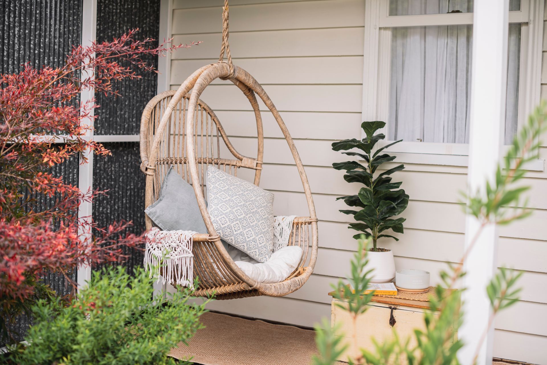 There is a hanging chair on the porch of a house.