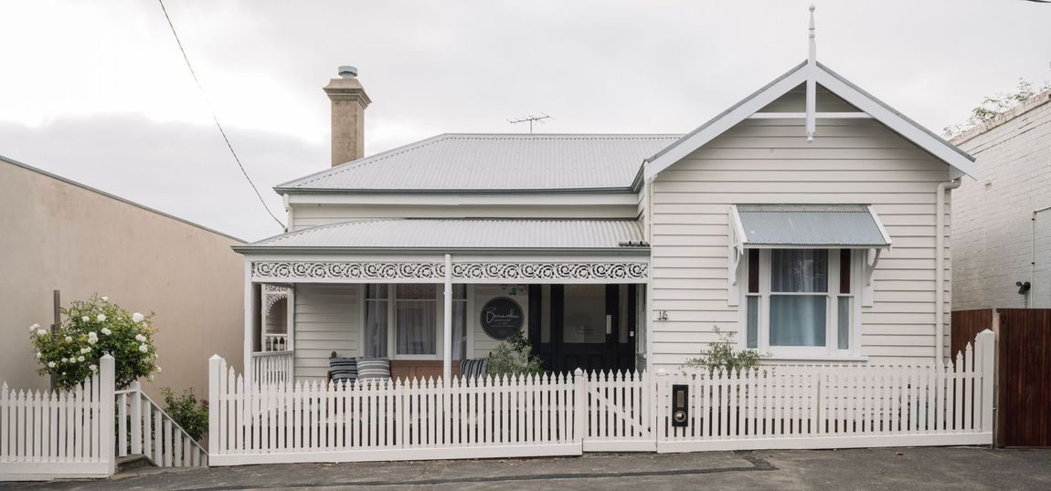 A small white house with a white picket fence in front of it.