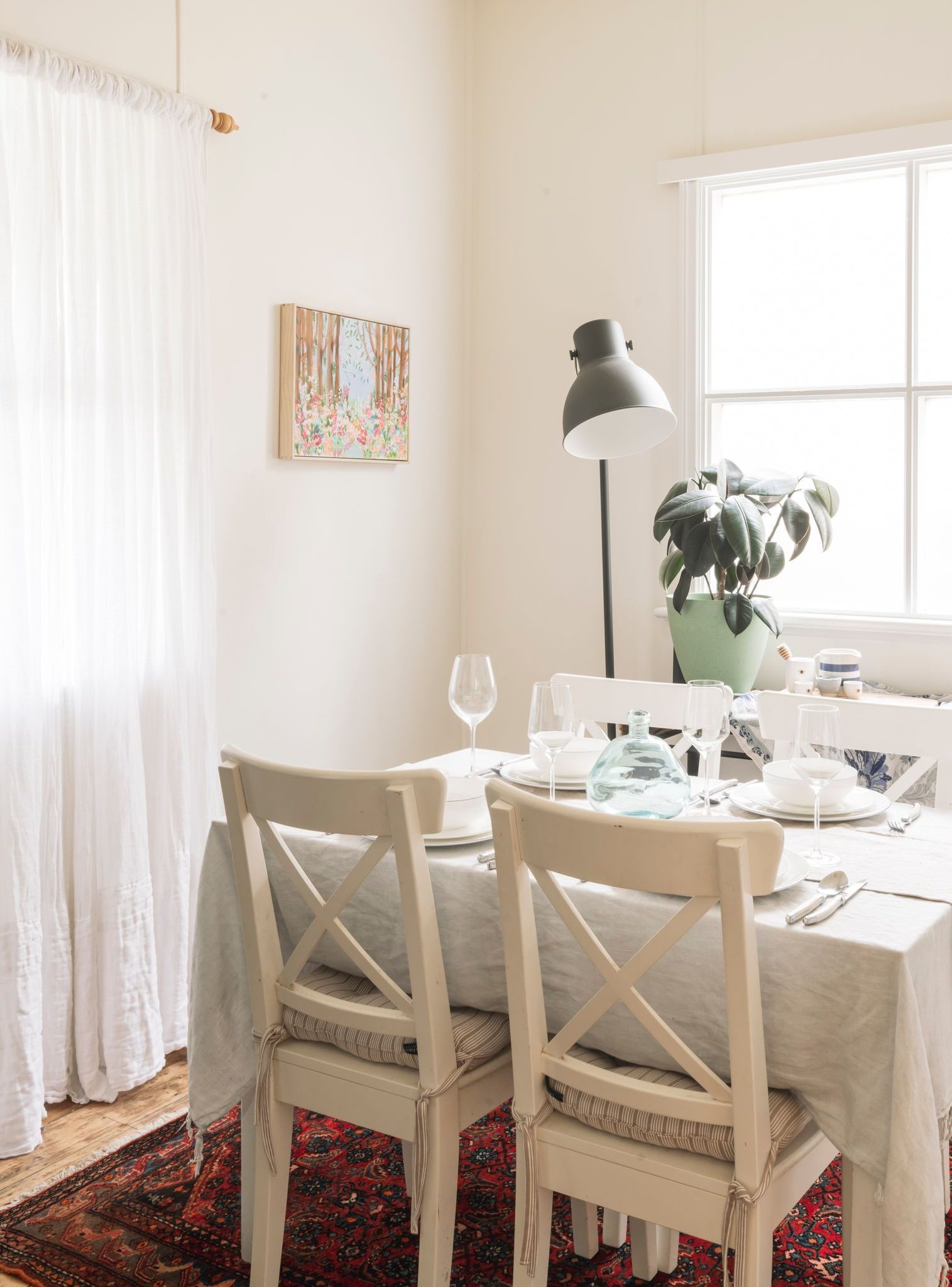 A dining room with a table and chairs and a lamp.