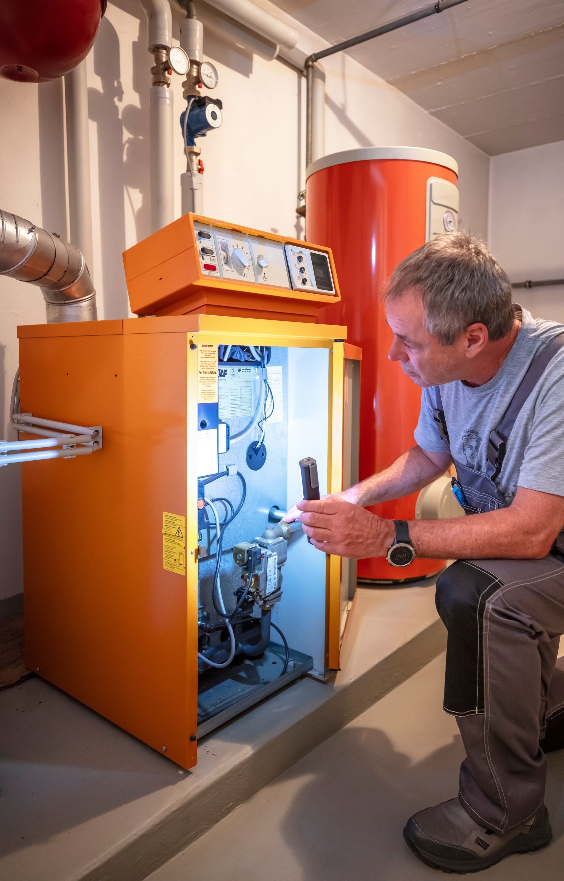 Un plombier-chauffagiste éclairant une chaudière orange