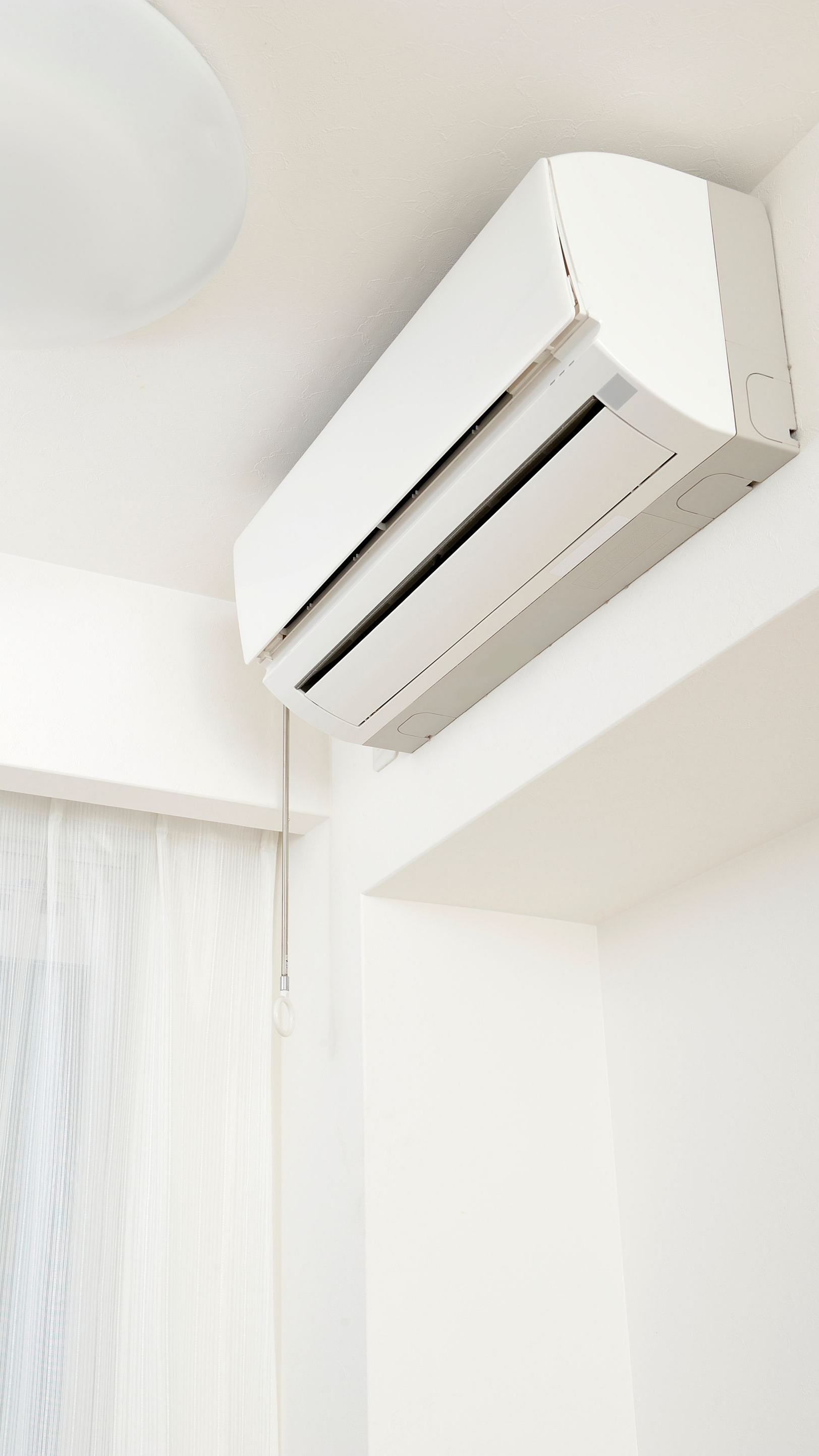 Climatiseur blanc fixé sur un mur blanc dans une pièce.