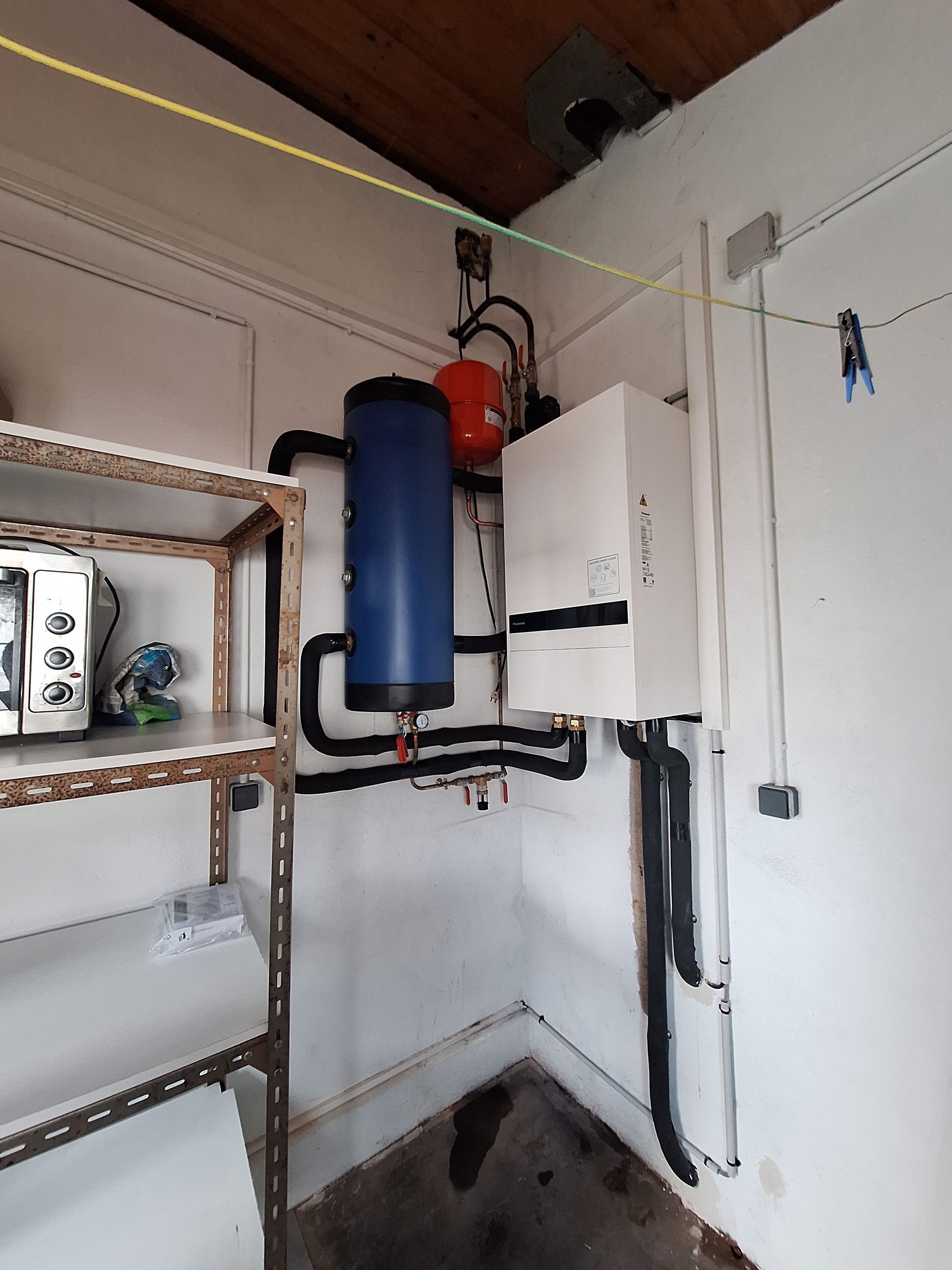 Système de chauffage avec réservoir bleu, vase d'expansion rouge et unité blanche dans un coin.