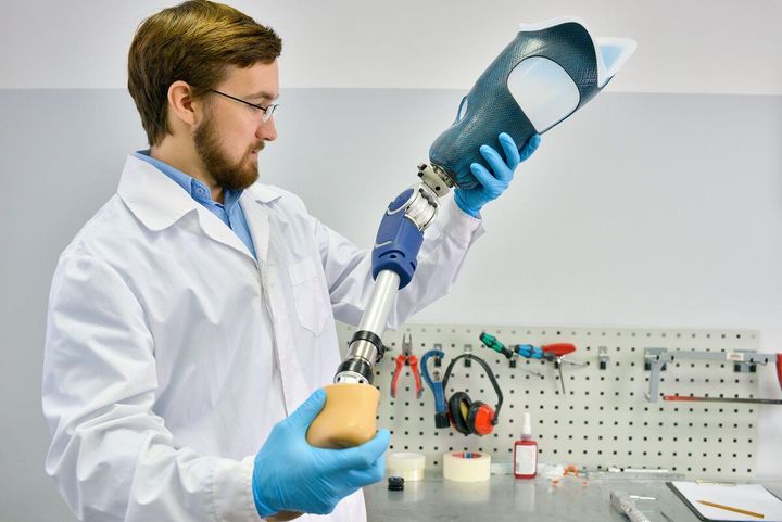 Ein Mann im Laborkittel hält eine Beinprothese in seinen Händen.