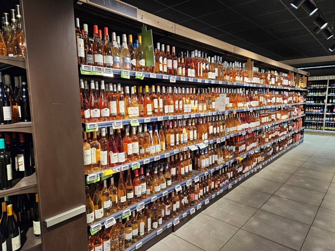 Reihen von Weinflaschen in Regalen in einem Geschäft, meist rosafarben.