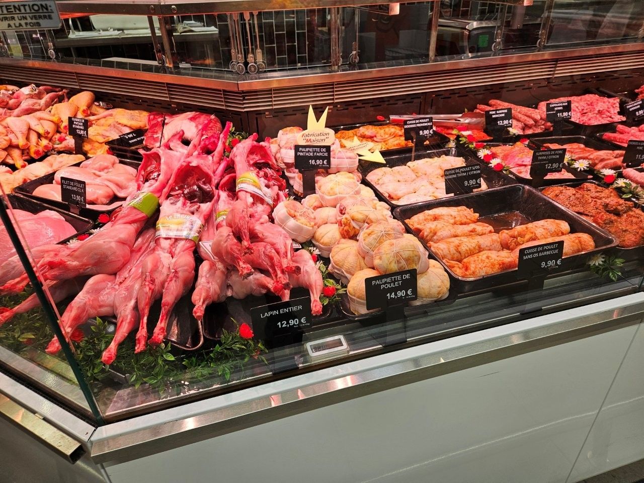 Fleischauslage: rohes Kaninchenfleisch, Hühnerfleisch und Fleischzubereitungen in einem Lebensmittelgeschäft.