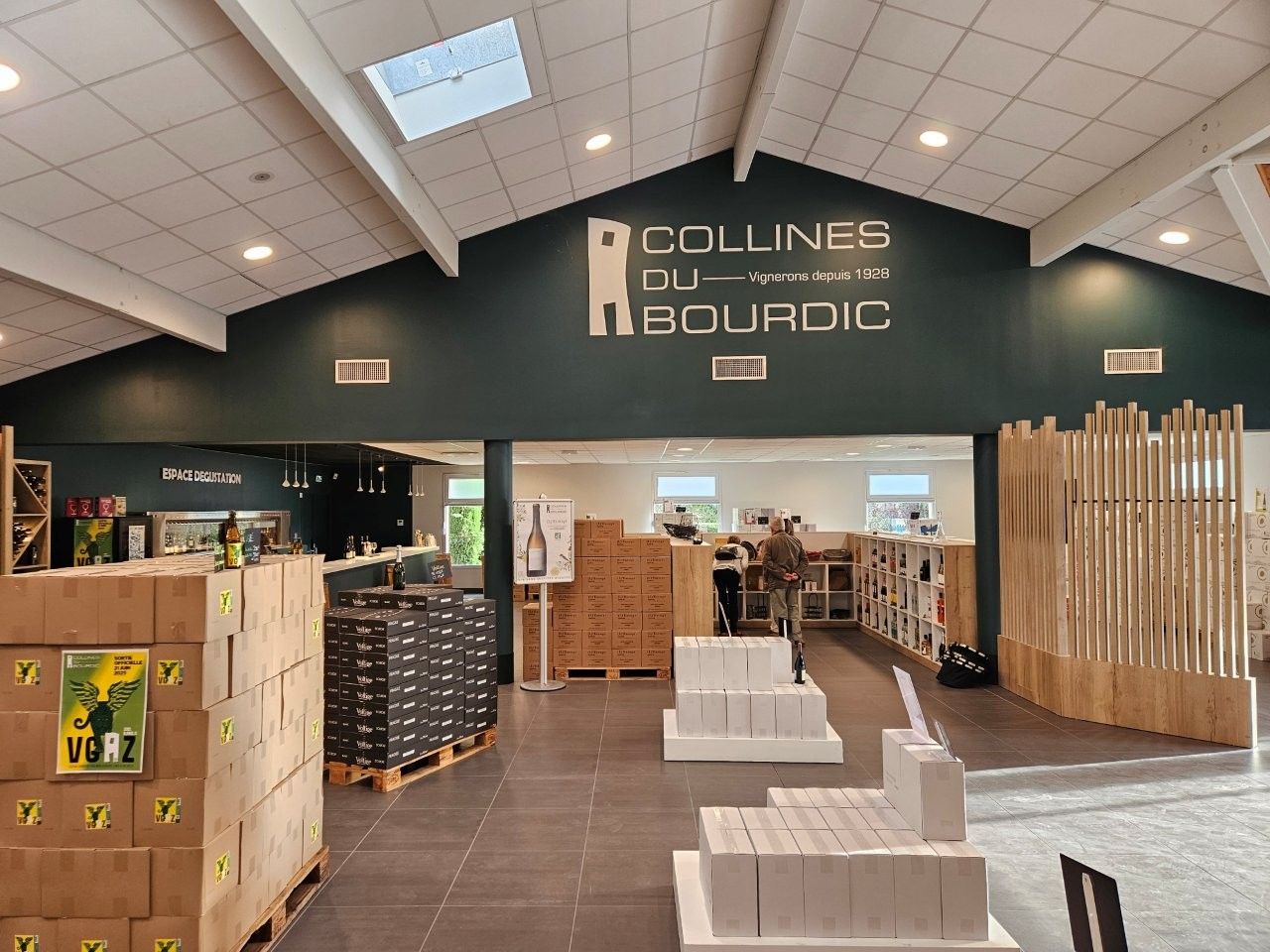 Innenaufnahme eines Ladens mit einem Schild „Collines du Bourdic”. Produkte und Auslagen sind zu sehen.