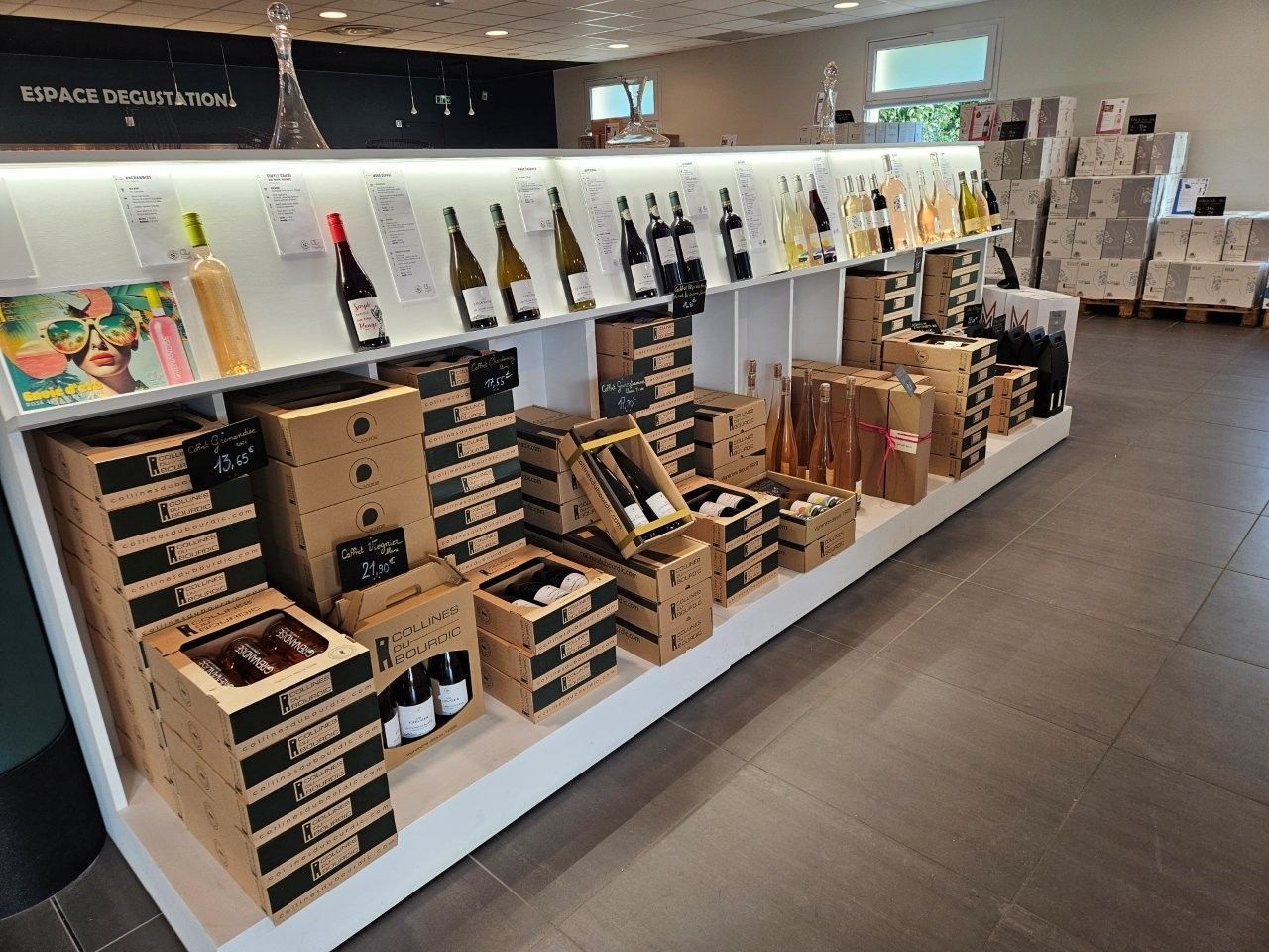 Weinflaschen und Box-Sets, die in einem Geschäft mit hellen Wänden und Böden in Regalen ausgestellt sind.