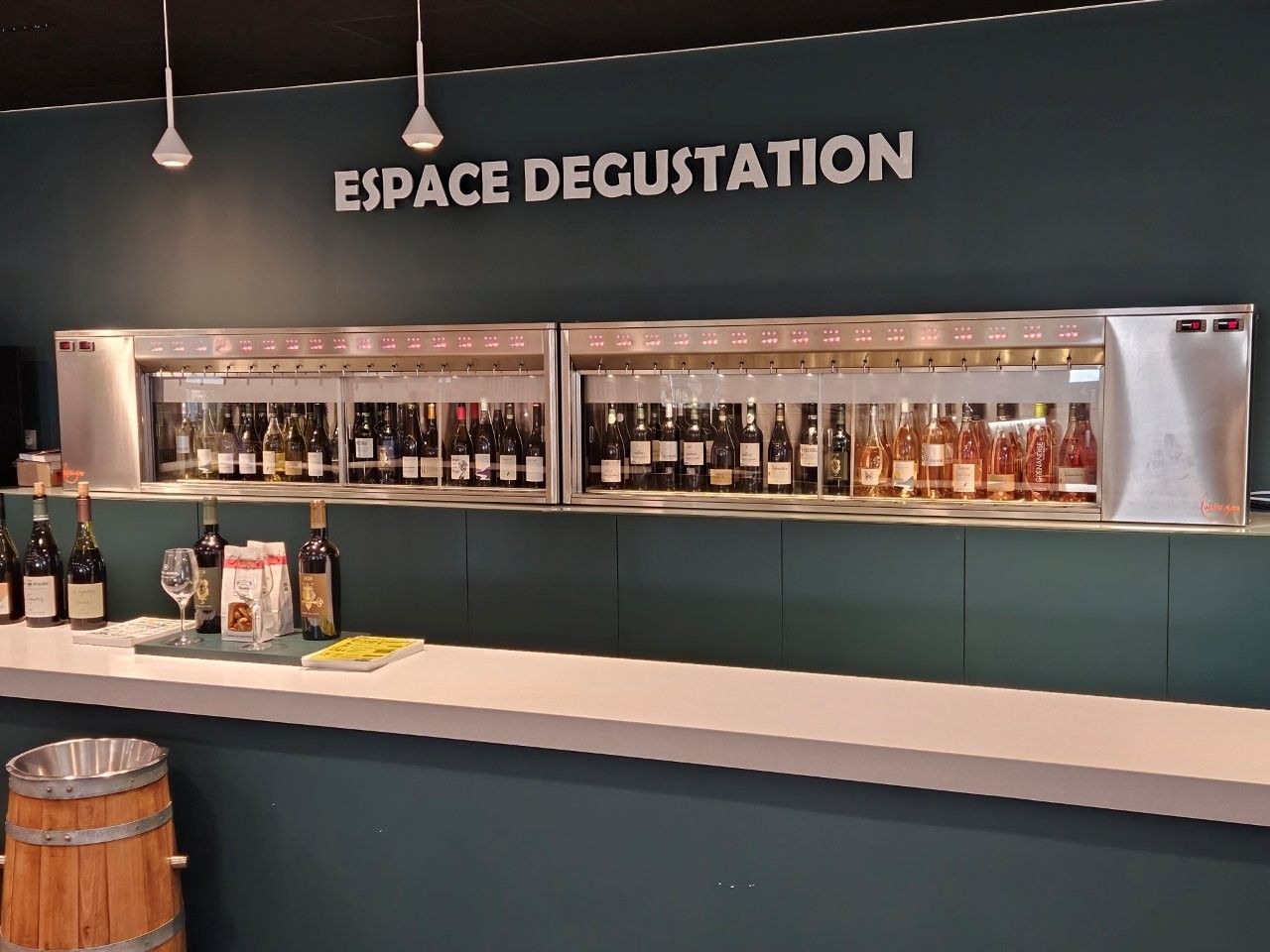 Weinverkostungsbereich mit zahlreichen Flaschen, die hinter einer langen Theke mit der Aufschrift „ESPACE DEGUSTATION” ausgestellt sind.