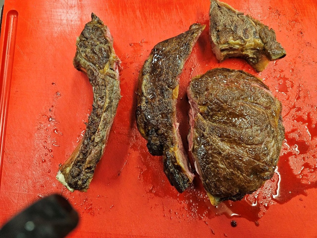 Gegrillte Steaks auf einem roten Schneidebrett.