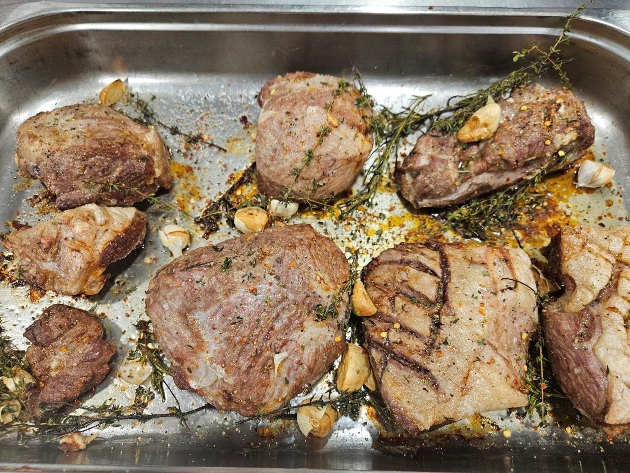 Gebratene Schweinefleischstücke mit Knoblauch und Kräutern in einer Metallbackform.
Feedback