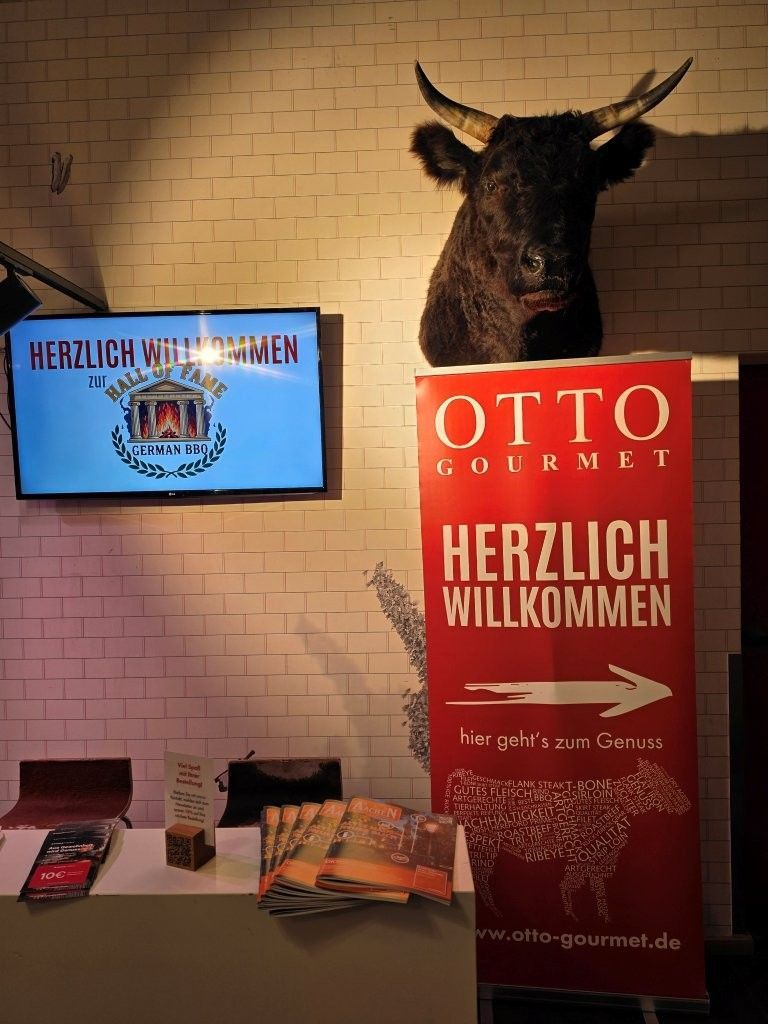 Warm lobby with illuminated sign, OTTO GARNETT welcome banner, moose head mount, and brochure table.