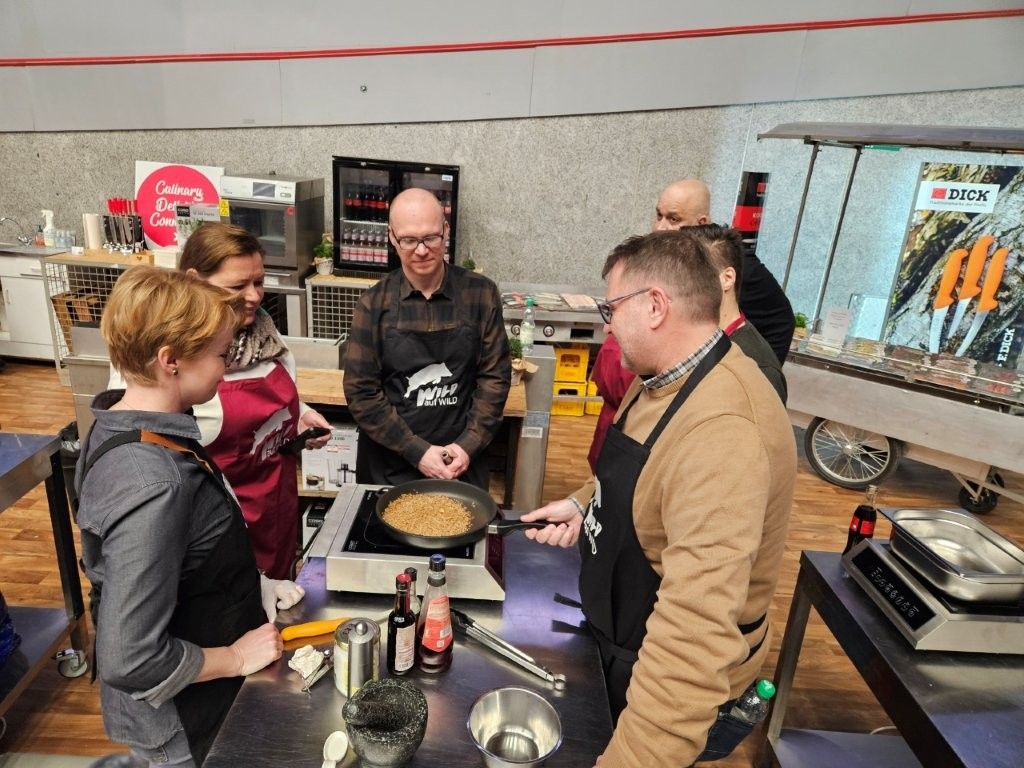 Eine Gruppe von Menschen in Schürzen kocht gemeinsam bei einer Vorführung.