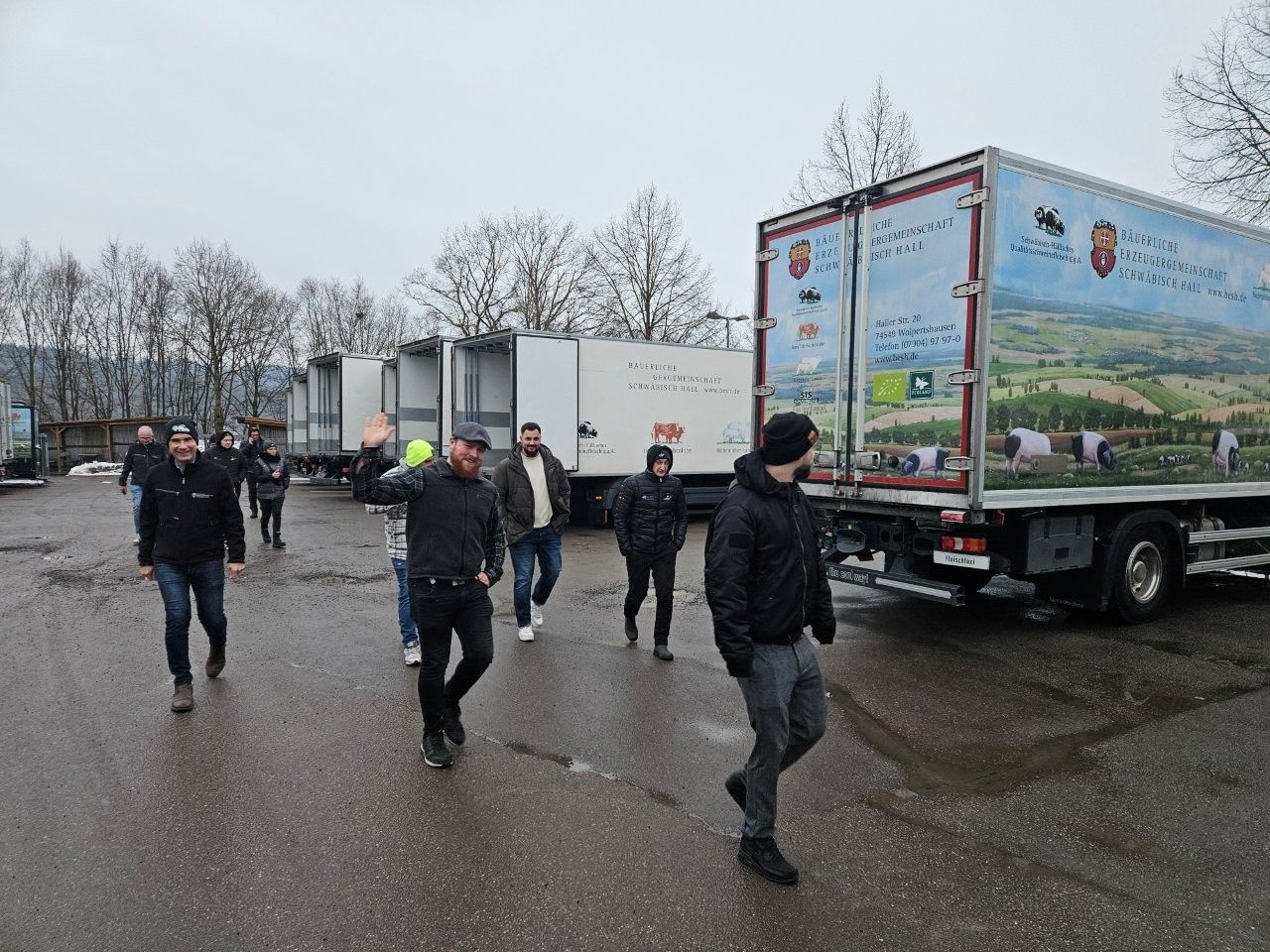 Menschen gehen an geparkten Lastwagen auf einem Parkplatz im Freien an einem bewölkten Tag vorbei.