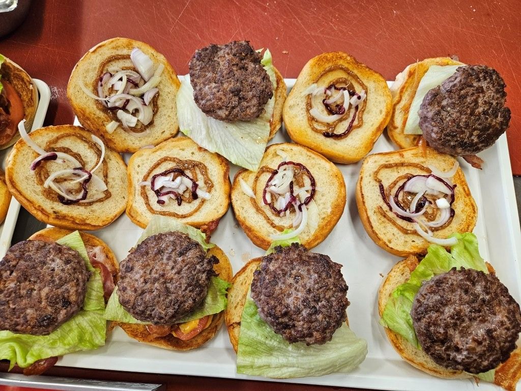 Tablett mit Mini-Burgern, bestehend aus Patties, Salat, Zwiebeln und Brötchen.