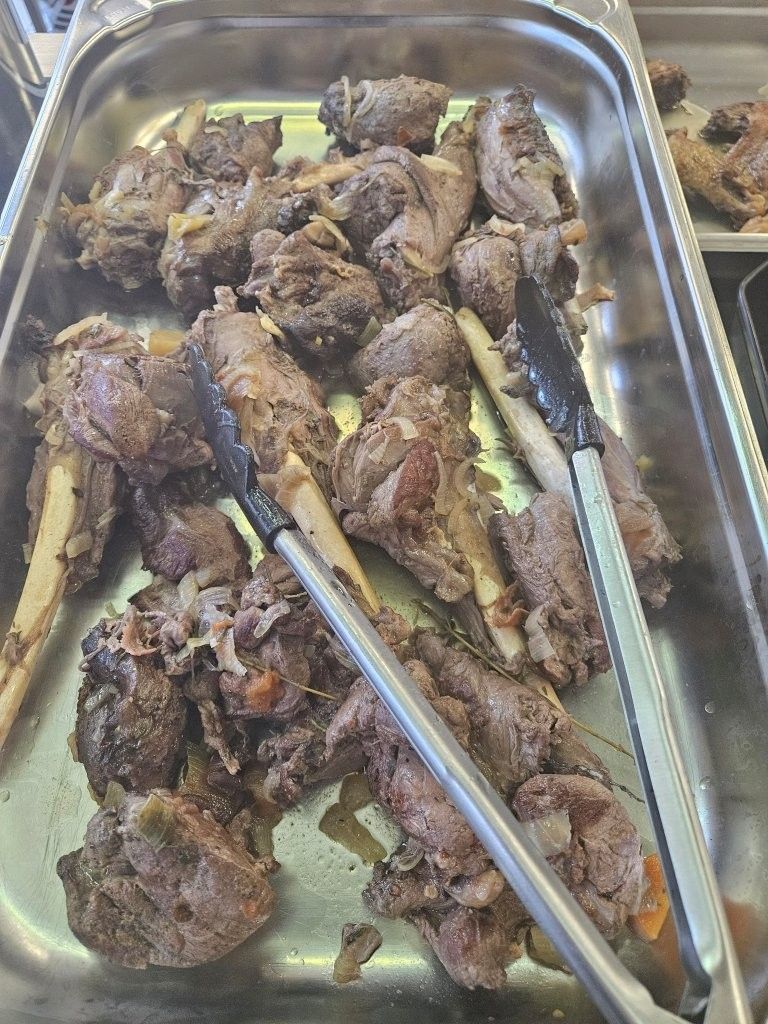 Gekochte Lammhaxen in einer Metallschale mit einer Zange.