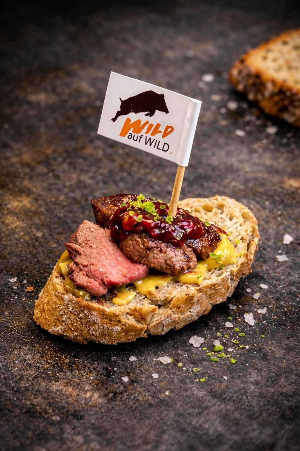 Eine Scheibe Brot, belegt mit Fleischscheiben, Soße und einer Flagge mit der Aufschrift „Wild but Wild“.