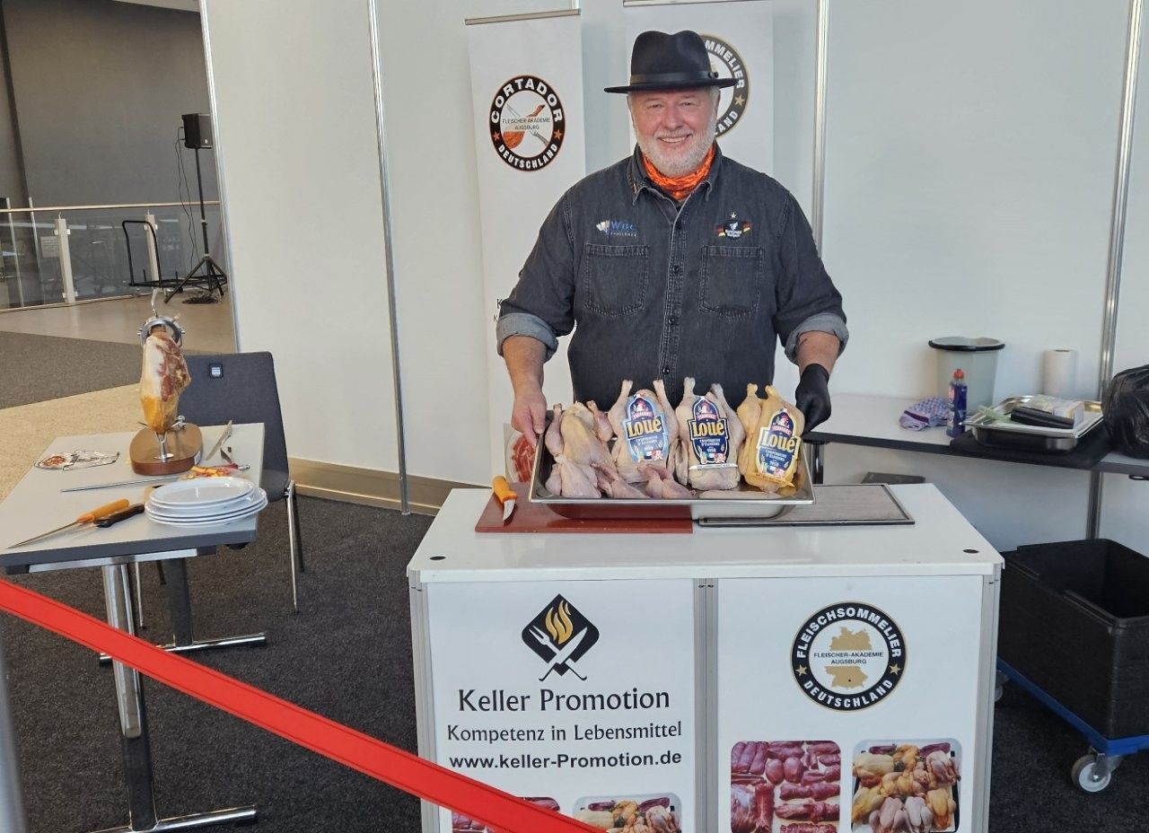 Mann mit Hut an einem Werbetisch mit verpackten Lebensmitteln.