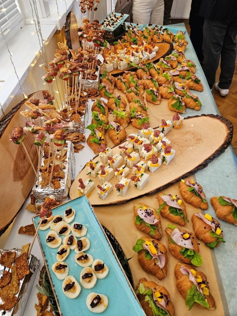 Verschiedene mundgerechte Vorspeisen und Gebäckstücke, die bei einem Buffet auf langen Tischen angerichtet sind