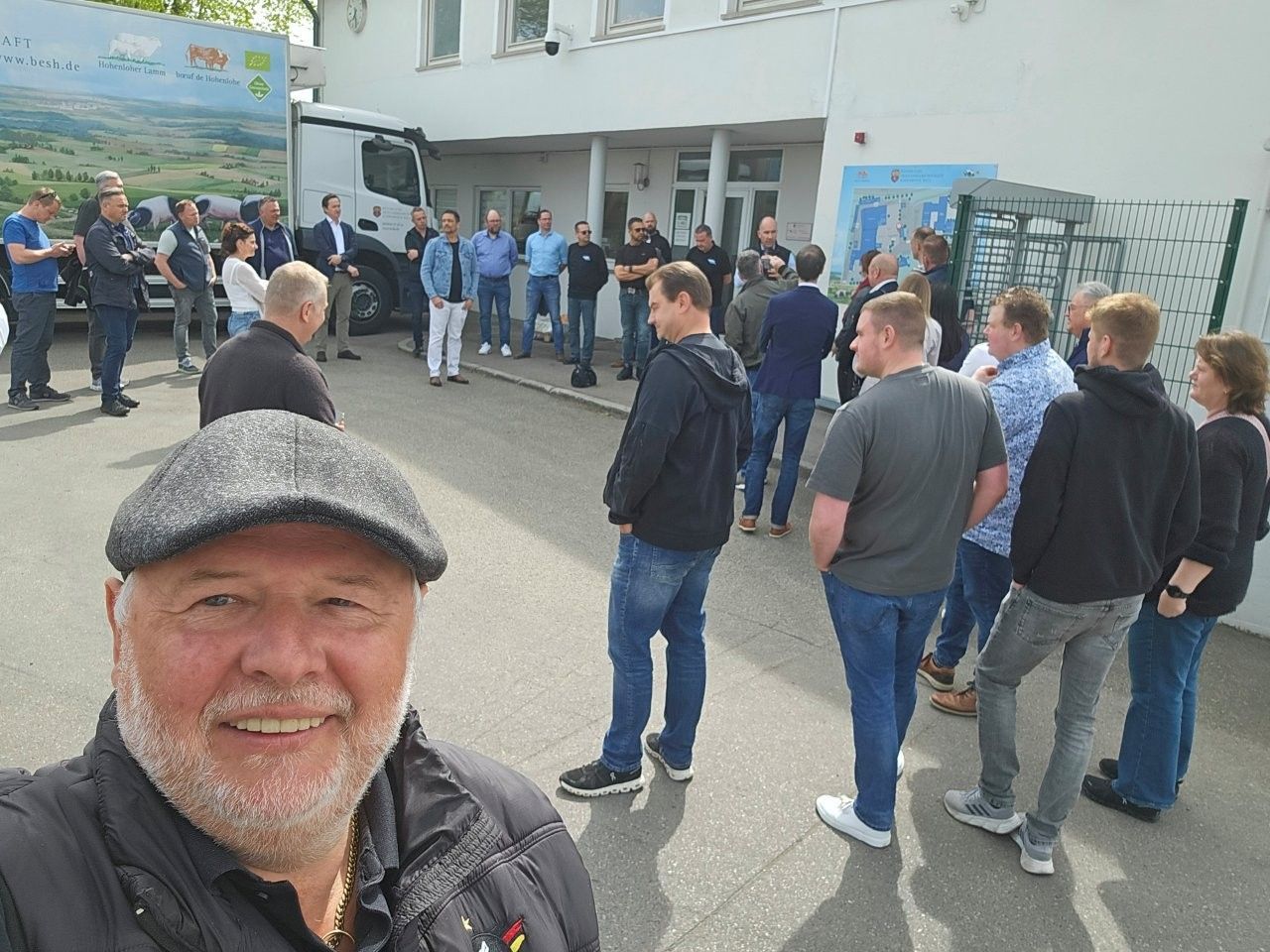 Selfie eines lächelnden Mannes bei einer Menschenmenge im Freien in der Nähe eines Gebäudes