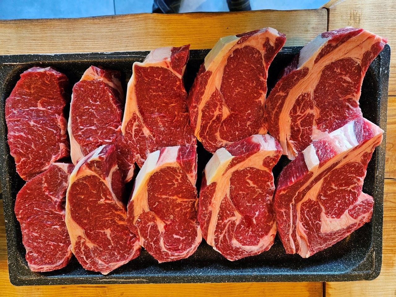 Rohe, marmorierte Rindersteaks auf einem Tablett angerichtet, bereit zum Kochen
