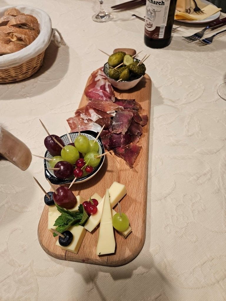 Eine Wurstplatte mit Trauben, Käse und Wurstwaren auf einer Tischdecke an einem Esstisch