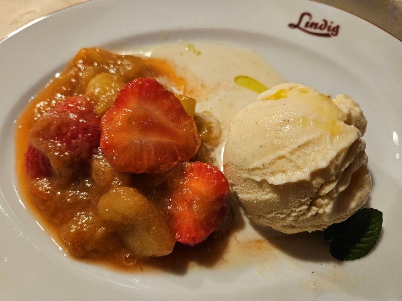 Dessertteller mit Erdbeerkompott und einer Kugel Vanilleeis auf einem weißen Teller