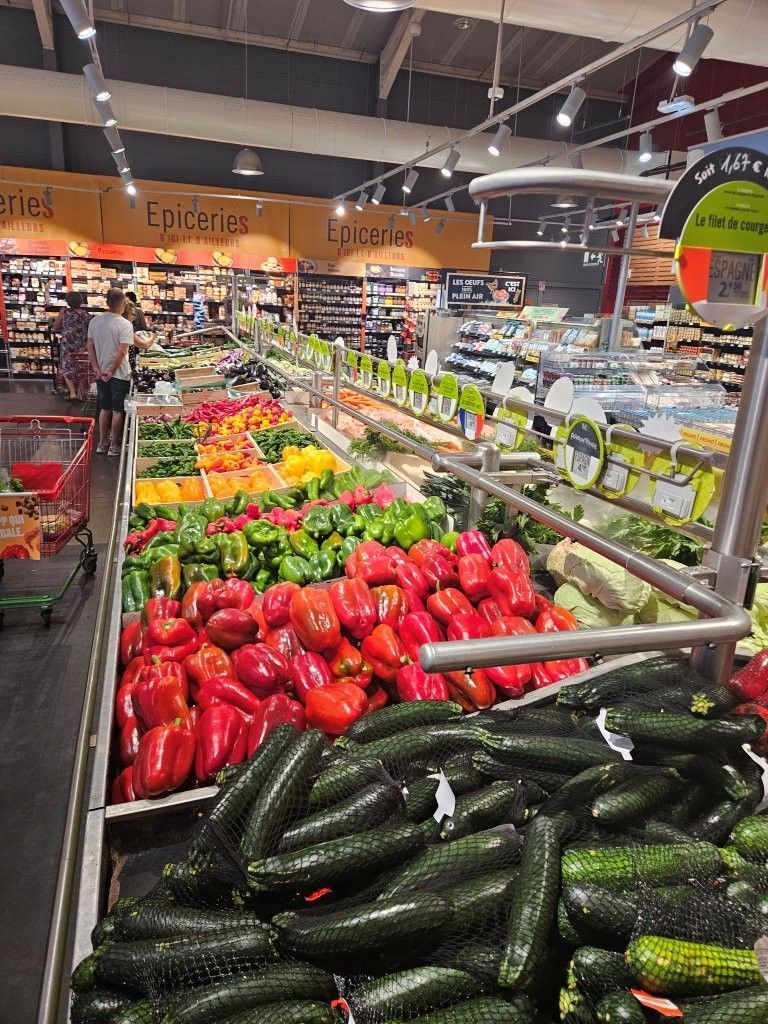 Die Obst- und Gemüseabteilung im Supermarkt mit farbenfrohen Paprika, Gurken und anderem frischen Gemüse.