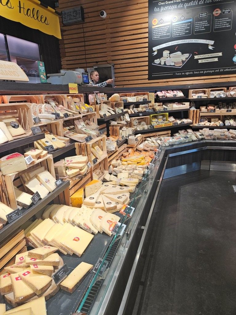 Feinkosttheke mit Brot, Gebäck und abgepackten Lebensmitteln unter Menütafeln