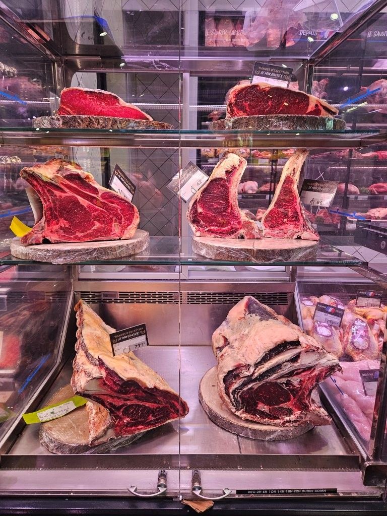 Glasvitrine mit großen Stücken rohem rotem Fleisch auf Regalen in einer Metzgerei