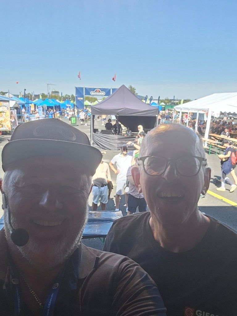Zwei lächelnde Menschen auf einem Freiluftmarkt unter strahlend blauem Himmel