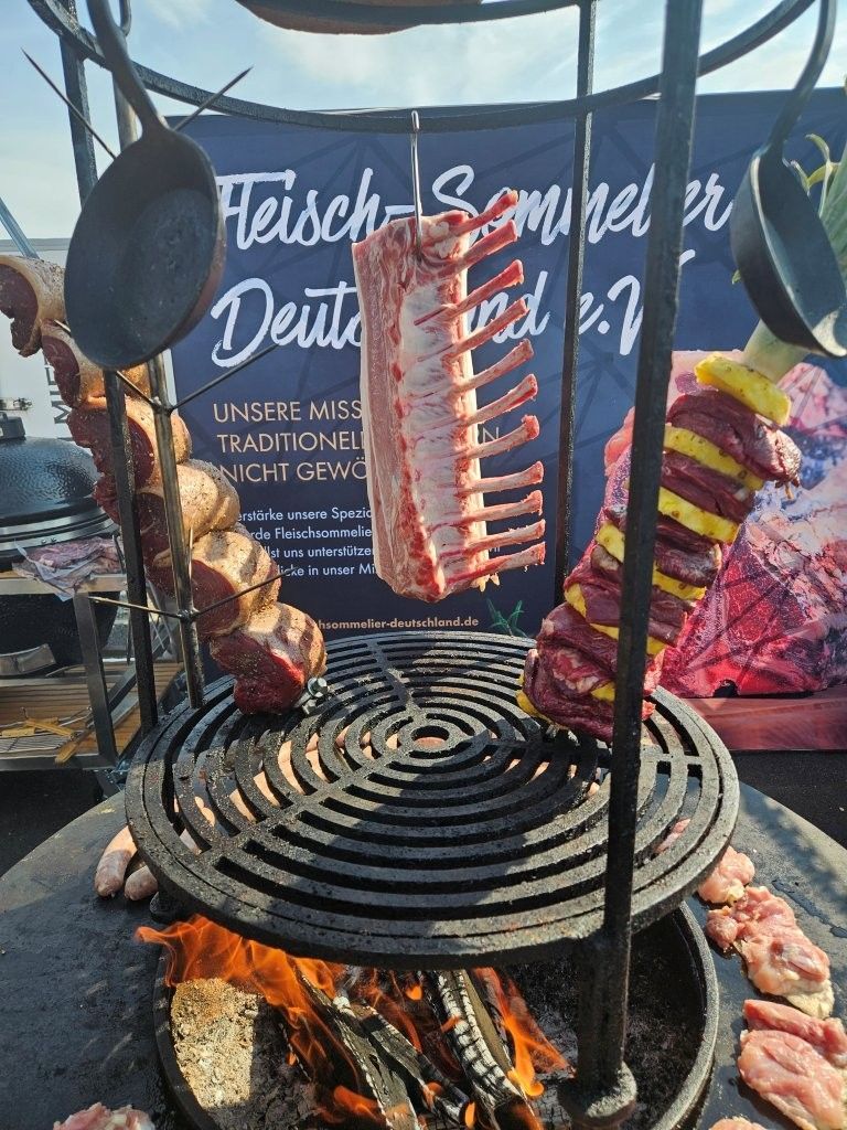 Ganze Schweine und Würstchen werden auf einem Freiluftmarkt an einem vertikalen Spieß über offenem Feuer gebraten.