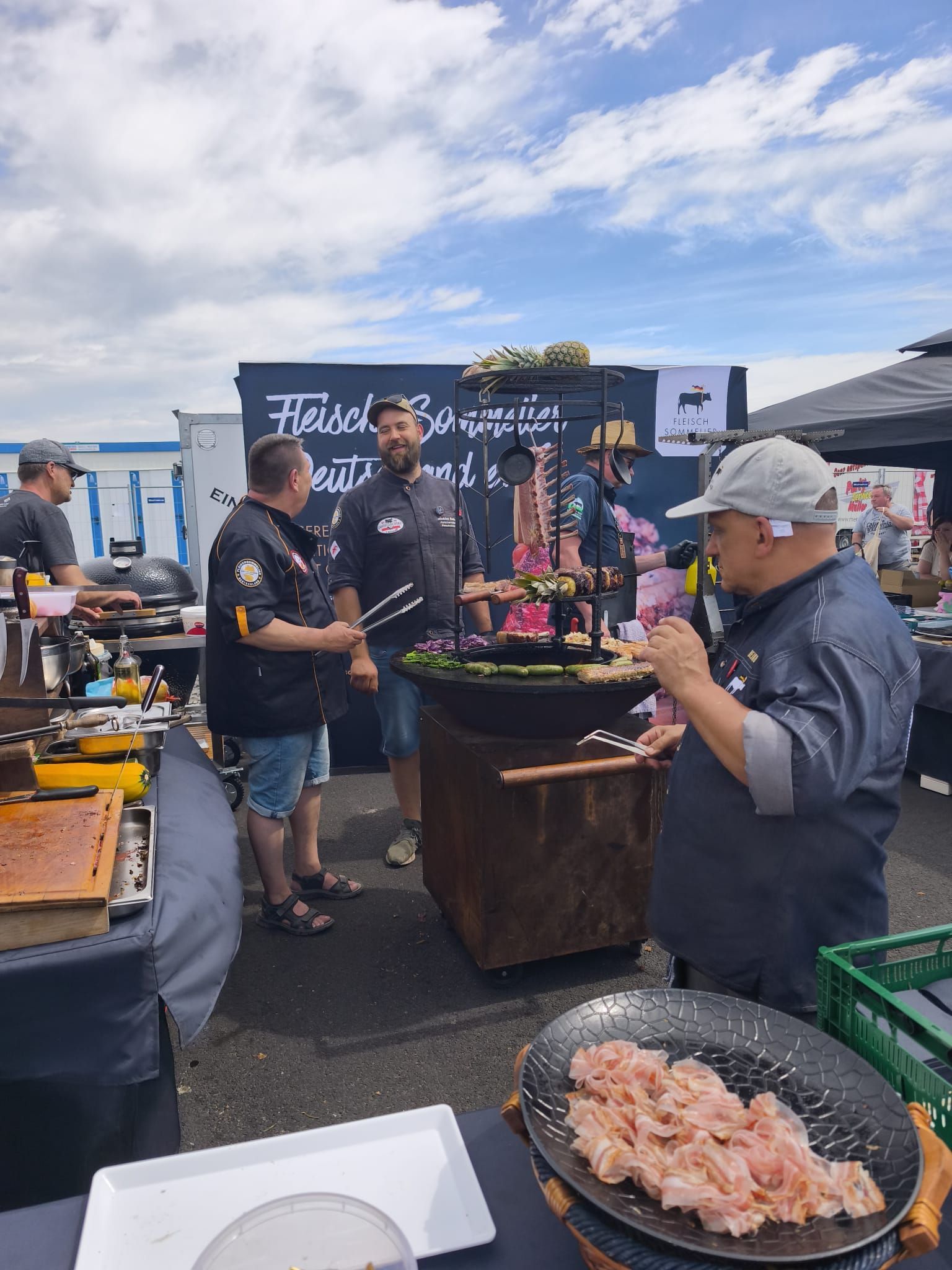 Fischmarkt im Freien mit Verkäufern, Kühlboxen und Tabletts mit frischen Meeresfrüchten unter einem bewölkten Himmel