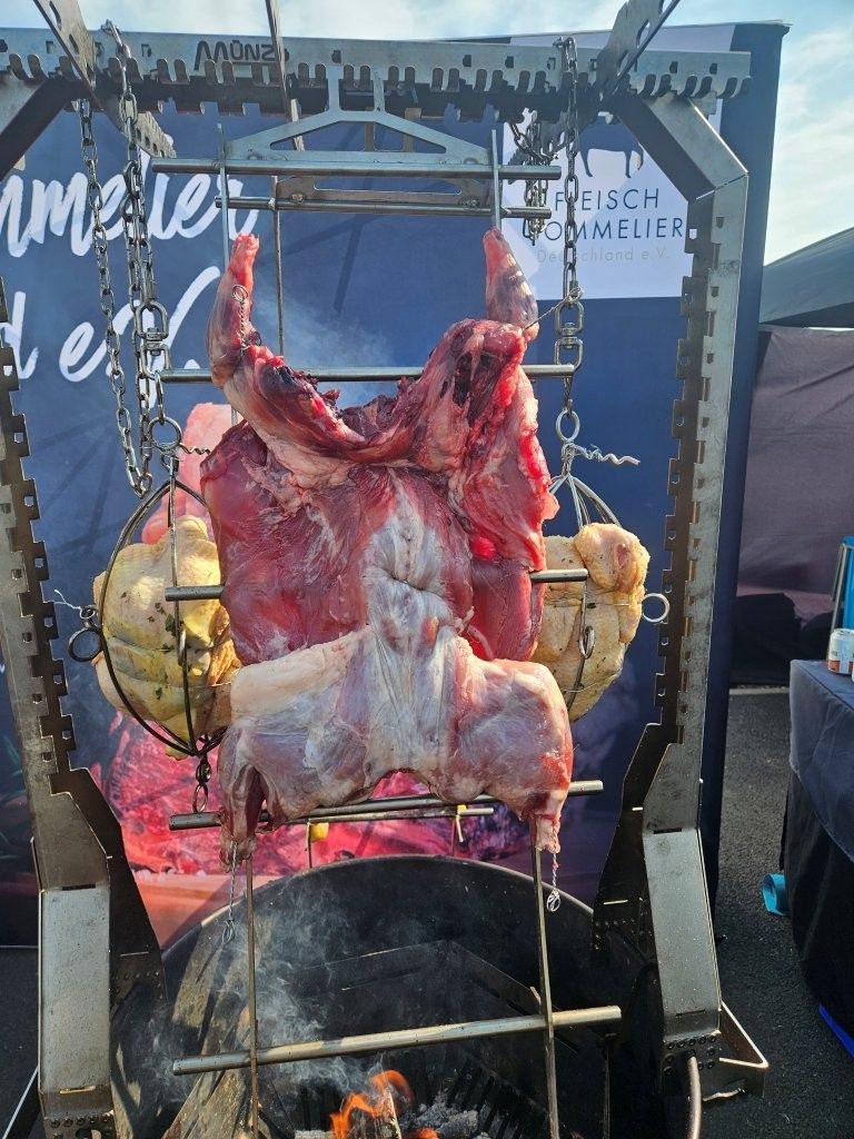 Ein ganzes Lamm wird an einem Spieß an einem Imbissstand im Freien gebraten.