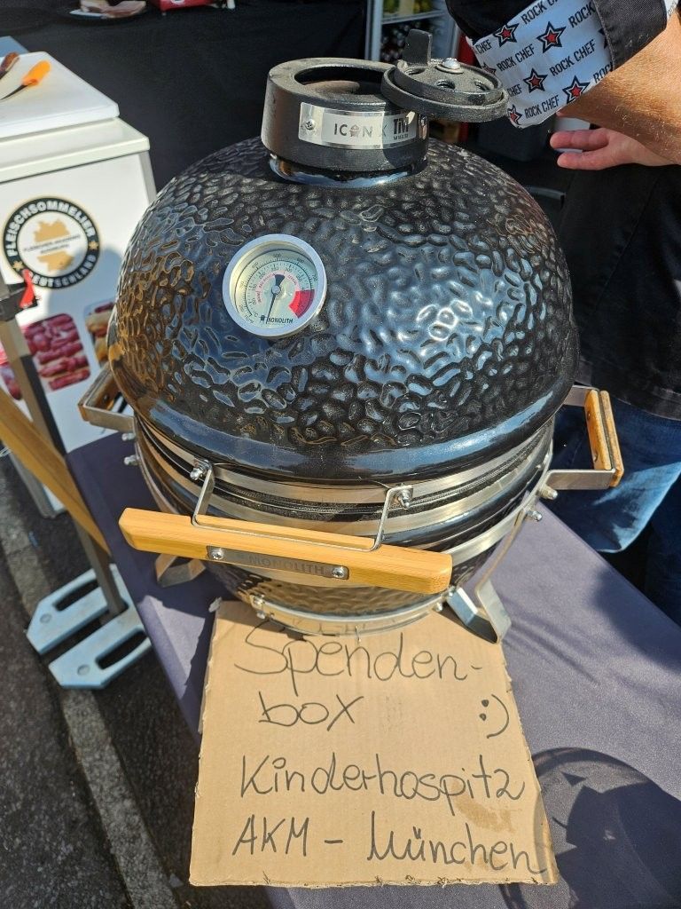 Schwarzer, strukturierter Keramikgrill auf einem Karton, im Hintergrund eine Hand, die ein Telefon hält.