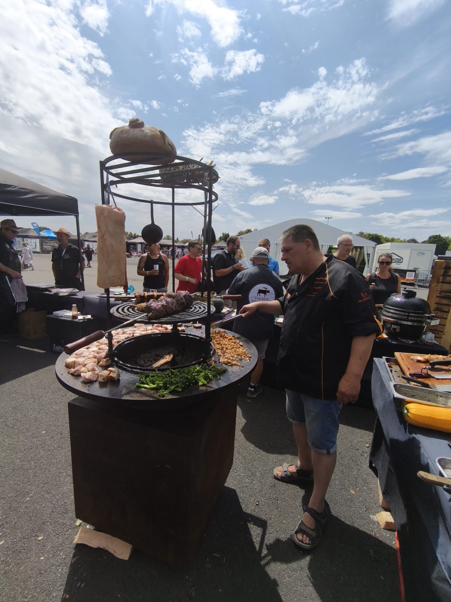 Grillbuffet im Freien mit großen Grills und Servicekräften unter sonnigem Himmel