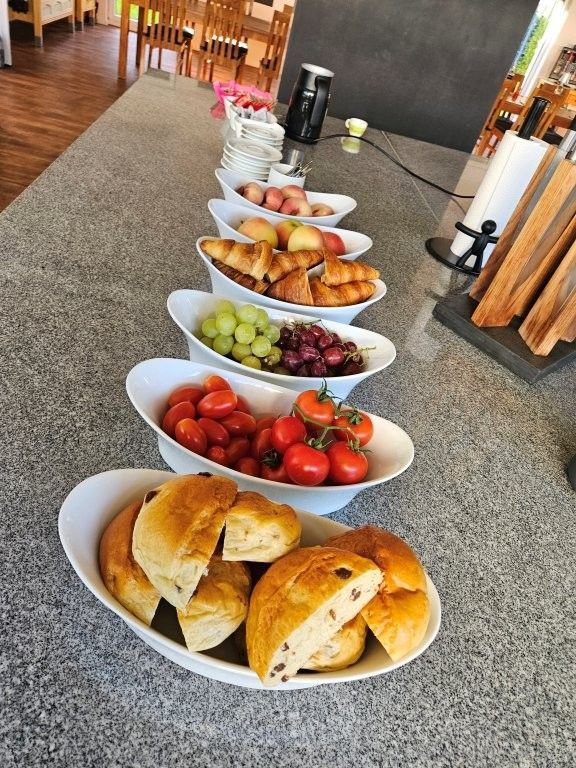 Buffet mit Schüsseln voller Brot, Erdbeeren, Weintrauben, Orangen und Getränken in einem Speisesaal