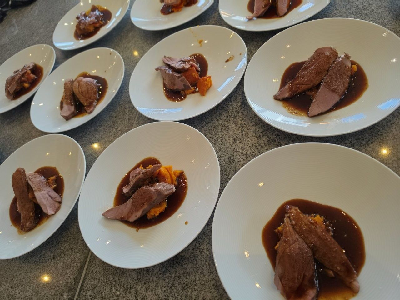 Platten mit aufgeschnittenem Fleisch und Soße auf einem Restauranttisch arrangiert