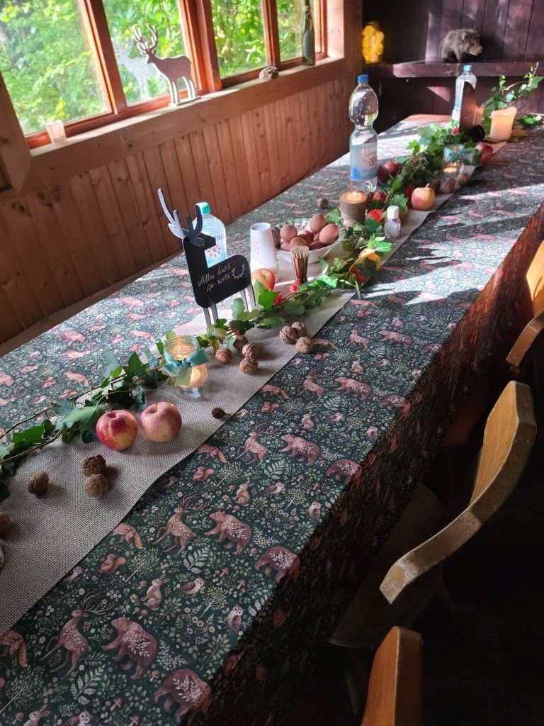 Langer Esstisch mit Obst, Blumen und Kerzen neben hellen Fenstern und Grünpflanzen