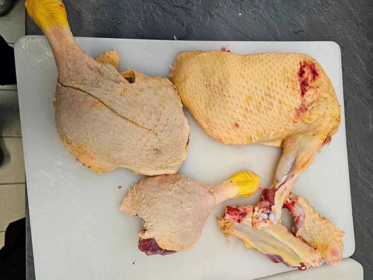 Hähnchenteile liegen auf einem weißen Schneidebrett