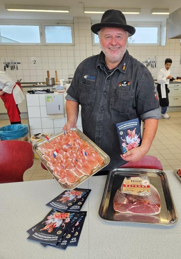 Ein Mann mit einem Hut hält ein Tablett mit Fleisch in der Hand.