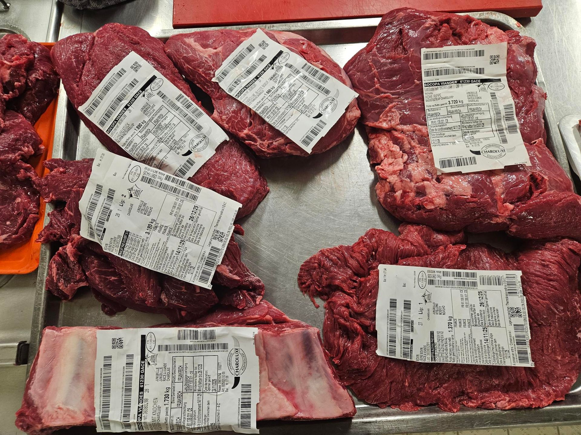 Fleischstücke mit Preisschildern auf einem Metalltablett in einer Metzgerei.