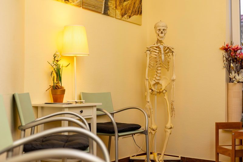 Ein Wartezimmer mit Stühlen und einem Skelett in der Ecke.