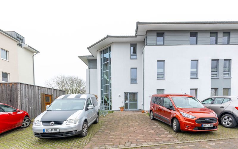 Vor einem Gebäude parkt eine Reihe von Autos.